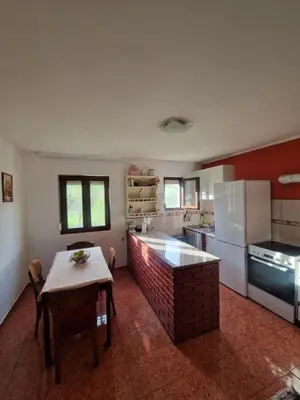 a kitchen with a table and a refrigerator and a table and chairs at Ivan's Holiday Home in Virpazar