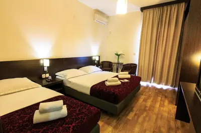 a hotel room with two beds and a television at Lucic Rooms & Suites in Budva