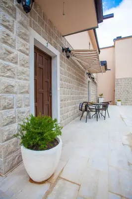a patio with a wooden door and a table and chairs at Rosmarino in Sveti Stefan
