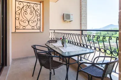 a table and chairs on a balcony with a window at Rosmarino in Sveti Stefan