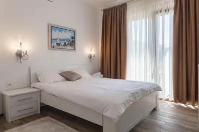 a bedroom with a white bed and a large window at Rosmarino in Sveti Stefan