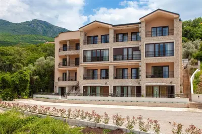 an apartment building with a view of the mountains at Rosmarino in Sveti Stefan