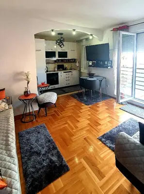 a living room with a wooden floor and a kitchen at Apartman Nina in Budva