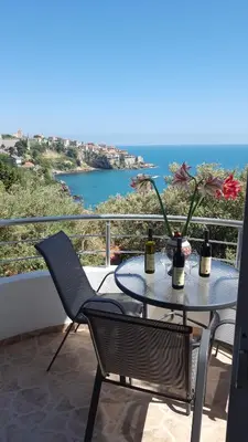 a table with two bottles of wine and flowers on a balcony at Apartments Sirena in Ulcinj