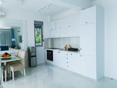 a kitchen with white cabinets and a table in it at Villa Blue Panorama in Budva