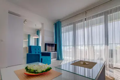 a living room with a glass table and blue chairs at Villa Blue Panorama in Budva