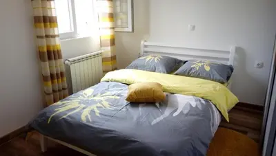 a bed with a yellow blanket and blue pillows at Apartments Maljevic in Bar