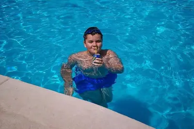 a woman in a swimming pool holding a toothbrush at Apartments Maljevic in Bar