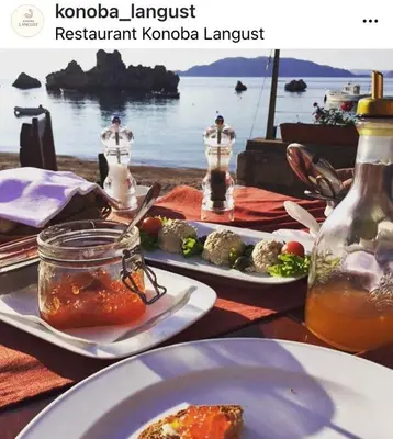 a table with plates of food and a view of the water at Apartments PROVA in Sveti Stefan