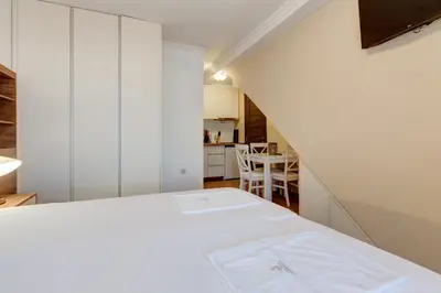 a room with a white bed and a kitchen at Apartments PROVA in Sveti Stefan