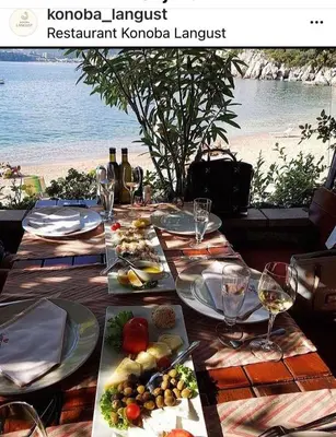 a table with plates of food and wine on the beach at Apartments PROVA in Sveti Stefan