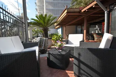 a patio with white wicker chairs and a table at Hotel Oaza in Budva
