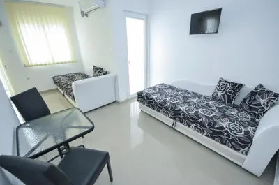 a white room with a bed and chairs in it at Hotel Oaza in Budva