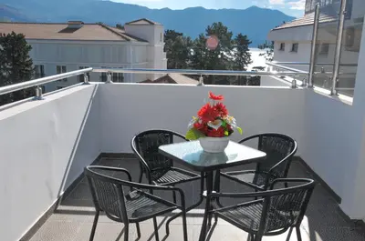 a table and chairs on a balcony with a vase of flowers at Hotel Oaza in Budva