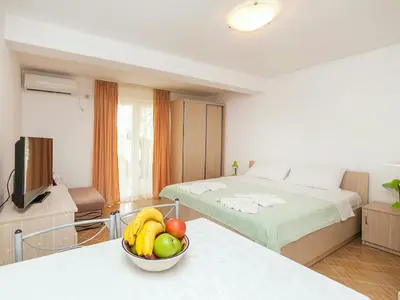 a room with a bed and a bowl of fruit on a table at Hana Accommodation in Sveti Stefan