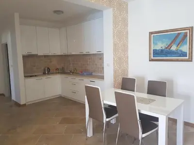 a kitchen with a white table and chairs at Apartmani Svetionik in Budva