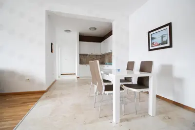 a white dining room with a white table and chairs at Apartmani Svetionik in Budva