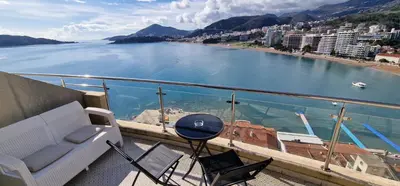 a balcony with a couch and chairs and a view of the water at Apartmani Svetionik in Budva