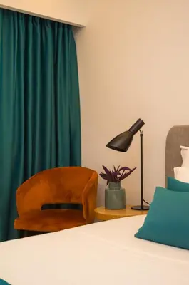 a bedroom with a bed and a chair and a lamp at Hotel Admiral in Budva