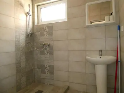 a bathroom with a sink and a shower with a window at Apartments In Amor in Ulcinj