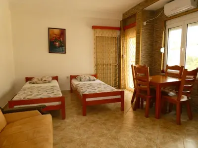 a room with two beds and a table and chairs at Apartments In Amor in Ulcinj