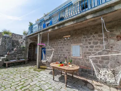 a patio with a table and hammocks on a building at Holiday House Stari Volat in Budva