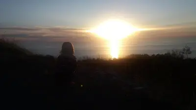 a woman sitting on a hill watching the sunset at Holiday House Stari Volat in Budva