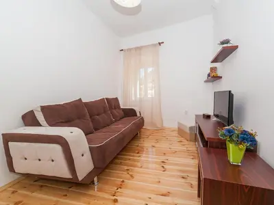 a living room with a brown couch and a television at Apartments Kaleta in Kotor
