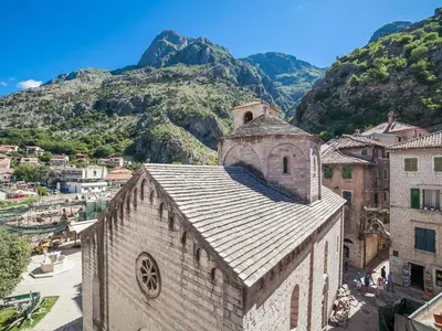 an old church in a town with mountains in the background at Apartments Kaleta in Kotor