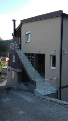 a cat walking in front of a building with stairs at Vip Apartmani Canj in Čanj