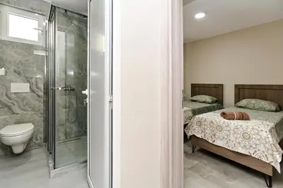 a bathroom with a shower and a bed and a toilet at Apartments Posejdon in Utjeha