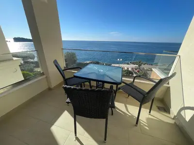 a balcony with a table and chairs and the ocean at Apartments Posejdon in Utjeha