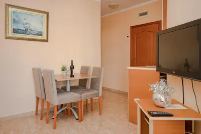 a living room with a table and a television at Apartments Posejdon in Utjeha