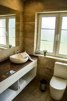 a bathroom with a sink and a toilet and two windows at Apartmani Mendula in Budva