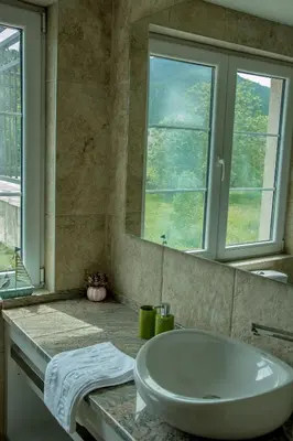 a bathroom with a tub and a sink and two windows at Apartmani Mendula in Budva