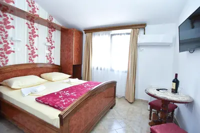 a bedroom with a bed and a table and a television at Hotel Grbalj in Budva