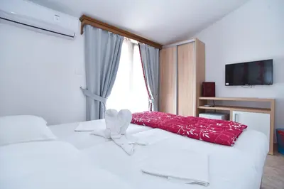 a bedroom with a white bed with a red pillow at Hotel Grbalj in Budva