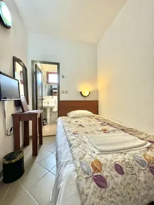 a bedroom with a bed and a television and a bathroom at Hotel Grbalj in Budva