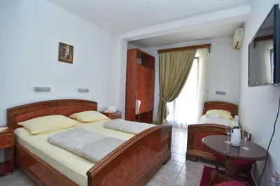 a bedroom with two beds and a table and a television at Hotel Grbalj in Budva