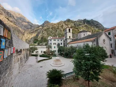 a group of buildings in a town with a mountain at Old town Kotor Square in Kotor