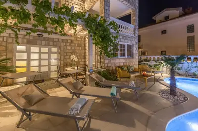 a patio with tables and chairs next to a pool at Apartments Captain's Villa in Budva