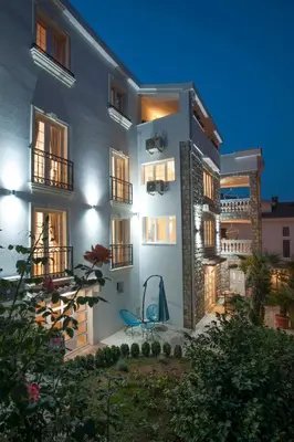 a large white building with a blue chair in front of it at Apartments Captain's Villa in Budva