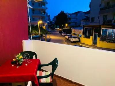 a red table and chairs on a balcony with a street at Apartment Oleander in Budva