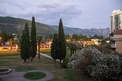a group of trees in a park with a building at Apartment Oleander in Budva