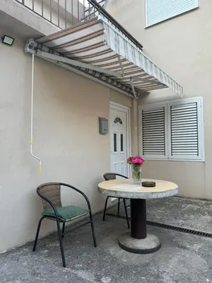 a patio with a table and a chair and a building at Apartmani Dada in Kotor