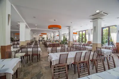 a dining room with white tables and wooden chairs at Hotel Aleksandar in Budva