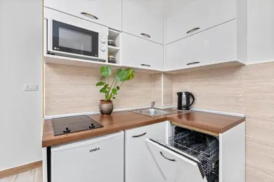a kitchen with white cabinets and a sink and a microwave at Apartments Casa Mia in Kotor