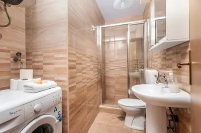 a bathroom with a toilet sink and a washing machine at Apartments Casa Mia in Kotor