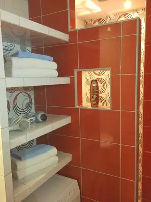 a bathroom with red walls and shelves with towels at Apartments Maris Garden in Petrovac na Moru