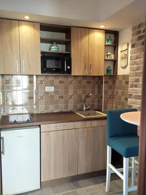a kitchen with wooden cabinets and a blue chair at Apartments Maris Garden in Petrovac na Moru